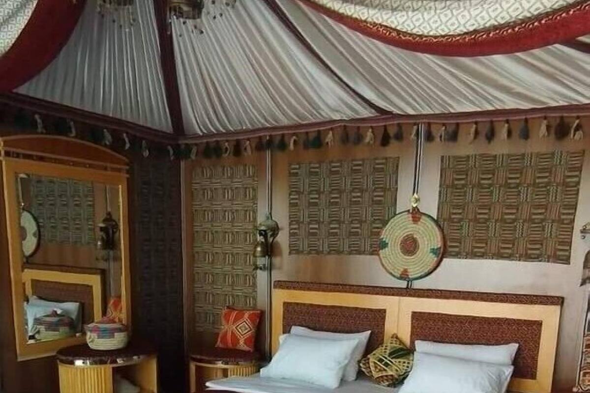 A traditional room with a bed, wooden headboard, and patterned wall decor.