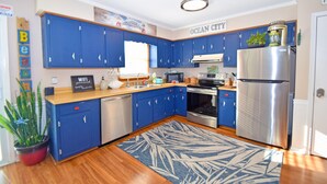 A modern kitchen with blue cabinets, stainless steel appliances, and a wooden countertop.