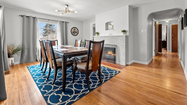 A dining area with a wooden table and chairs, a blue patterned rug, a fireplace, and a view of the outdoors.