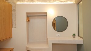 Une salle de bain avec un meuble en bois, un porte-serviettes, un miroir et une petite plante posée sur une étagère.