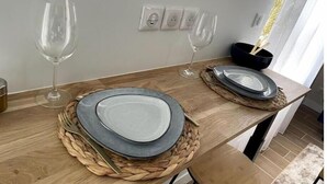Una mesa de comedor con platos, vasos, un posavasos tejido y un bol negro con palillos.