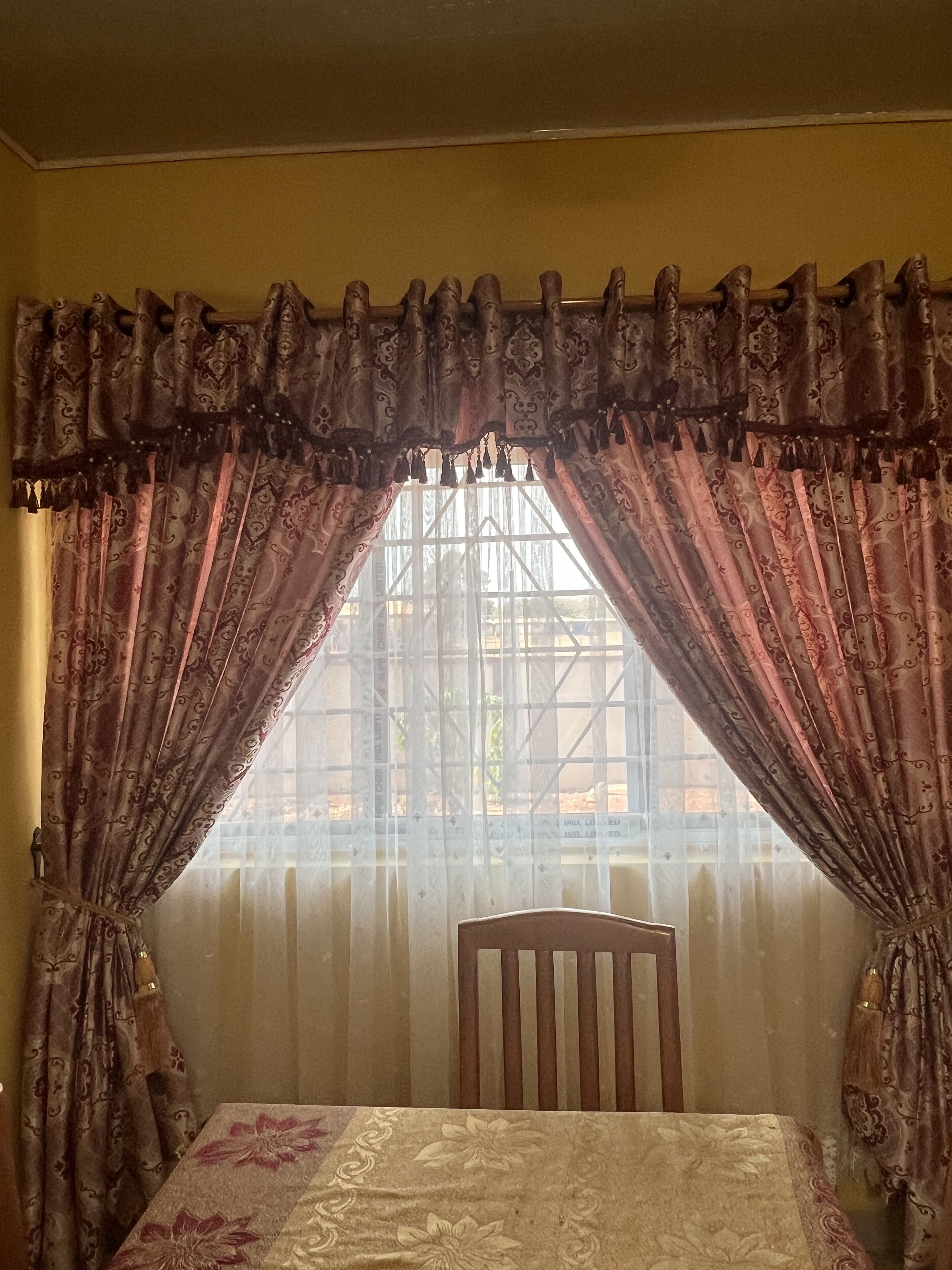 Um quarto com uma cama, uma cadeira e uma janela com cortinas.