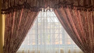 Um quarto com uma cama, uma cadeira e uma janela com cortinas.
