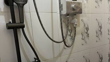 Zona de ducha con cabezal de ducha de mano, grifo empotrado y panel de control.
