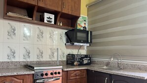 A kitchen with a microwave, stove, and sink. - Naayina Vacation Villas (Kogni)