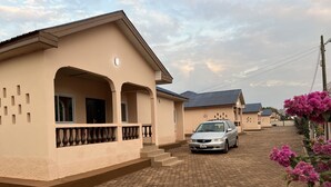 A residential street with houses, a parked car, and a cobblestone road. - Naayina Vacation Villas (Kogni)