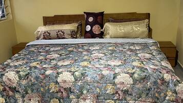 Una cama con colcha estampada, dos almohadas y un cabecero de madera.