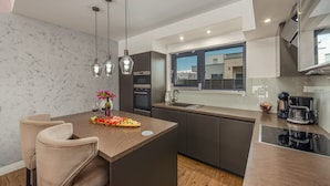A modern kitchen with a central island, pendant lighting, and a view to the outside. - Villa Lorena Dalmacija (Nin)