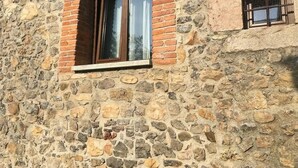 A stone building with a window and a small window with a metal grille. - Vivienda Vacacional Naguar Para 4 Personas en Triongo, Cangas de Onís (Triongo, Cangas de Onís)