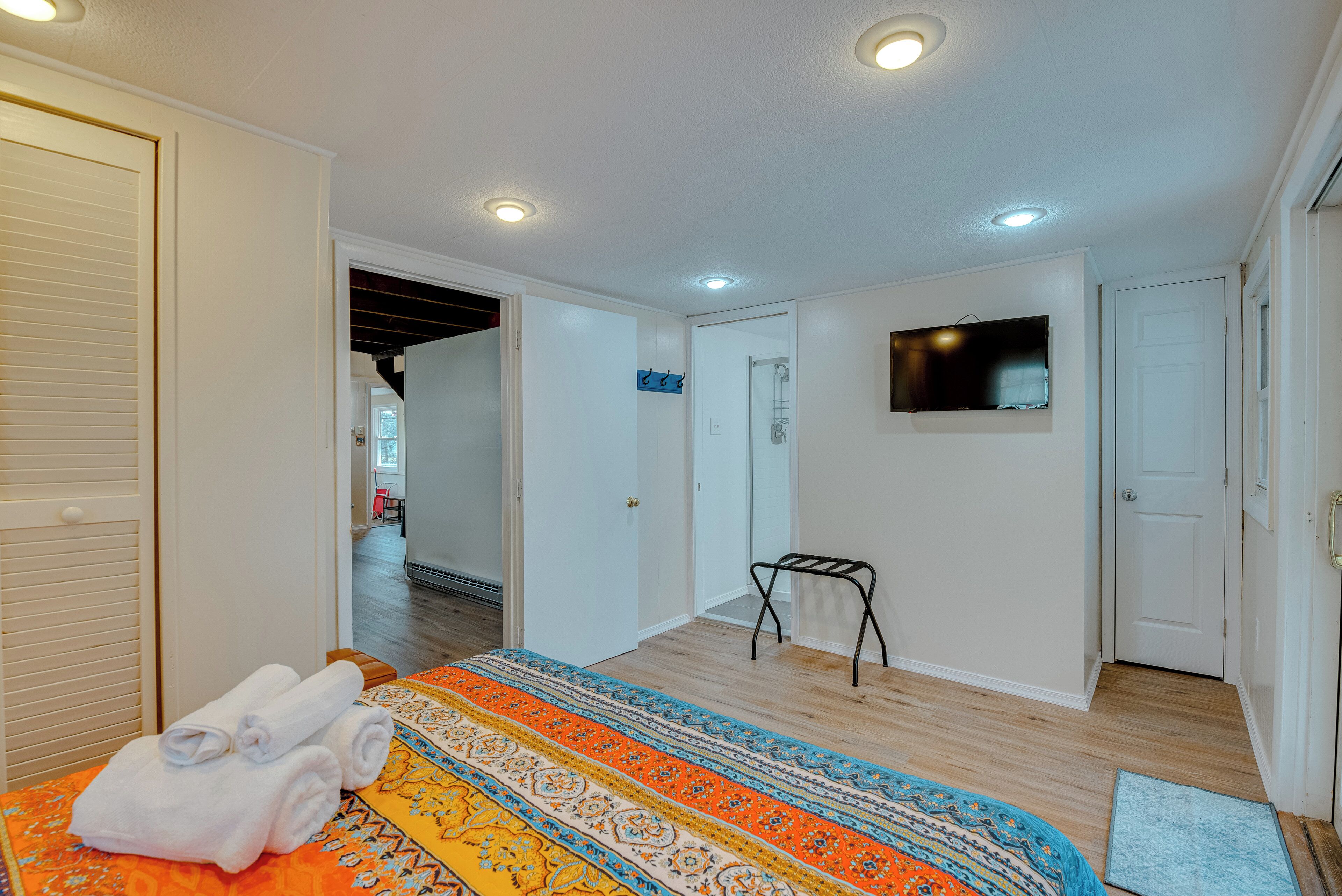 A bedroom with a bed, a TV, and a bathroom visible in the background.