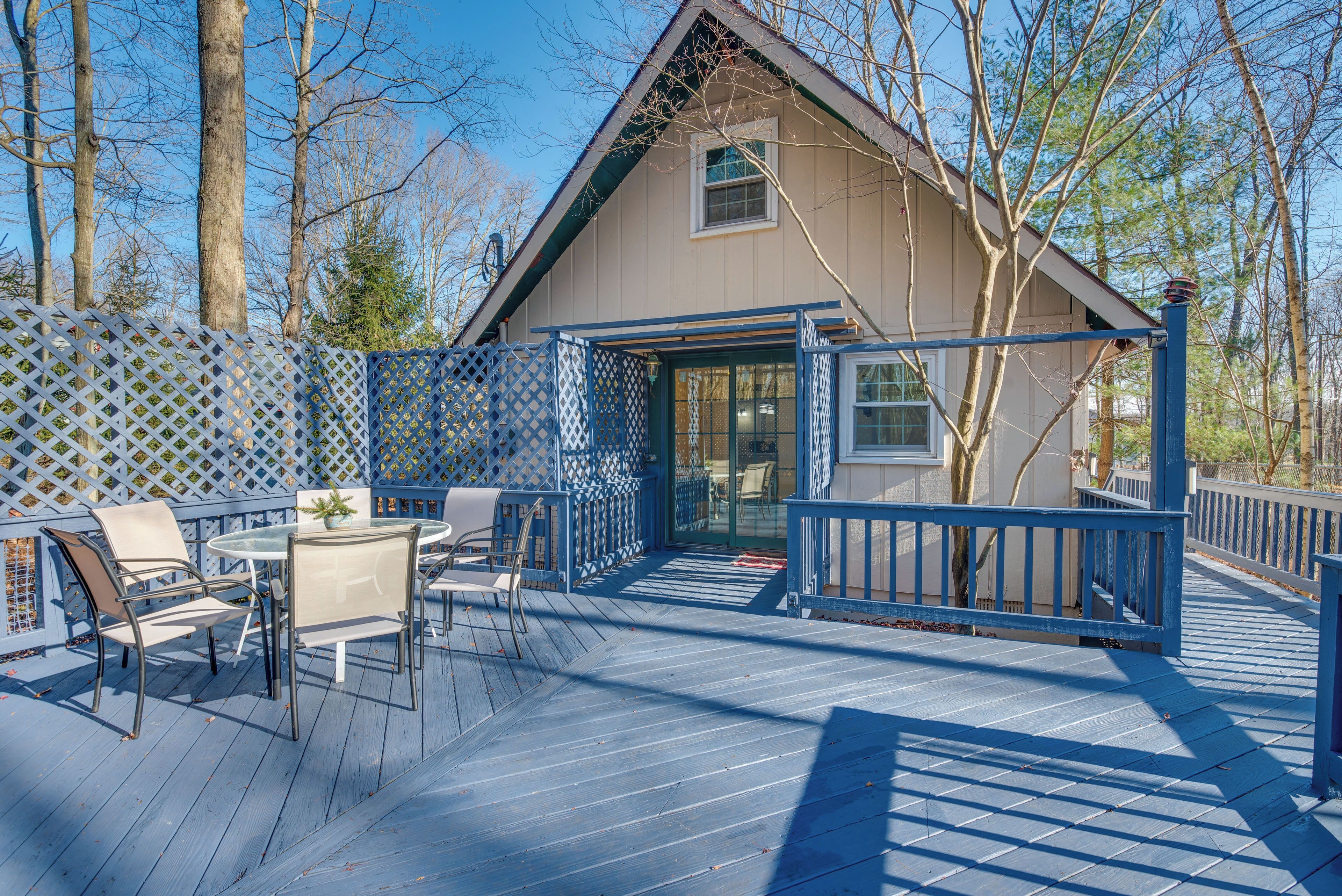 A wooden deck with outdoor furniture, a covered patio area, and a building with a gabled roof.