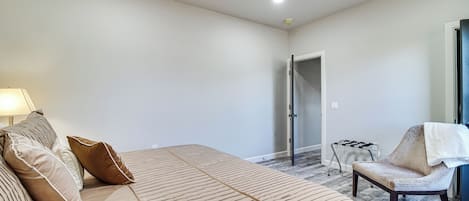 A bedroom with a bed, a chair, a ceiling fan, and a door.
