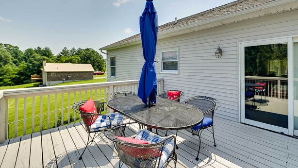 A covered patio with a table and chairs, a blue umbrella, and a view of a house and backyard. - Home w/ Private Pool - 15 Miles to Ark Encounter! (Berry)