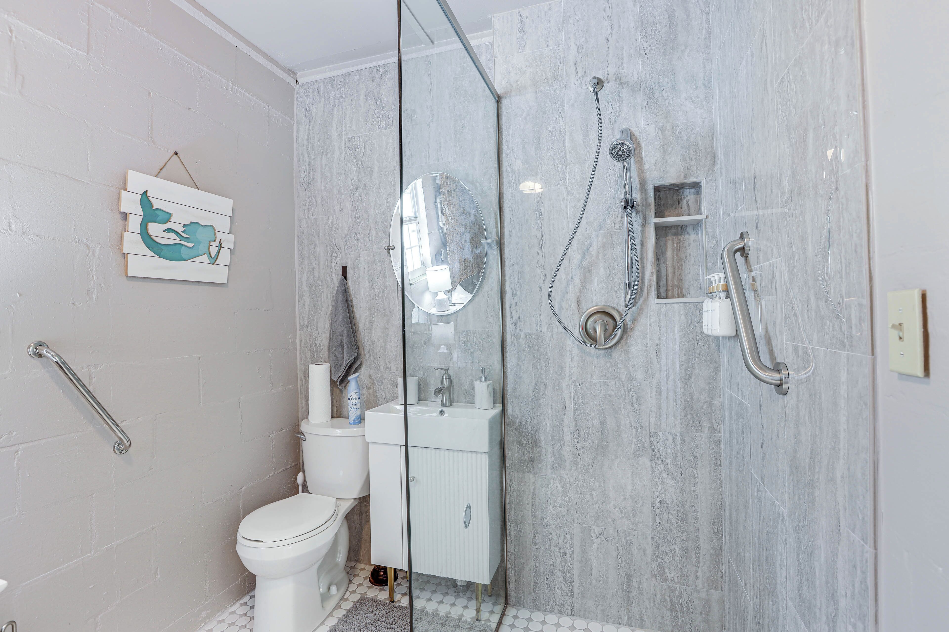 A modern bathroom with a glass shower enclosure, a white toilet, a sink, and a mirror.