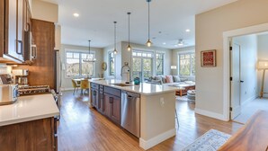A spacious kitchen with a central island, wooden cabinets, stainless steel appliances, and pendant lighting. - Winter Park Condo w/ Balcony ~ 4 Mi to Slopes (Winter Park)