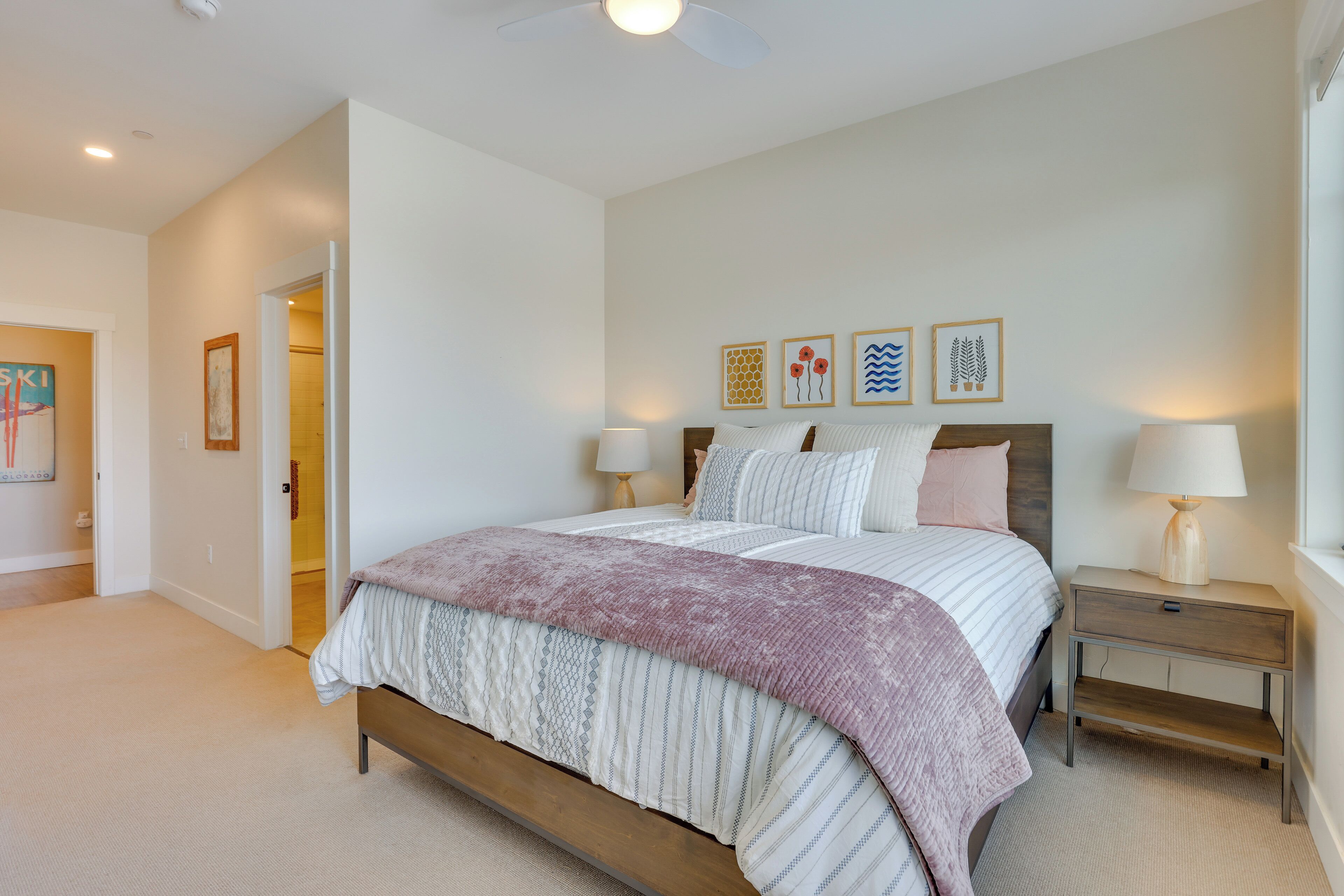 A bedroom with a bed, bedside tables, and wall art.