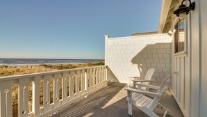 A balcony with white railings, two Adirondack chairs, and a view of the beach. - Scenic Bandon Vacation Rental w/ Beach Access! (Bandon)