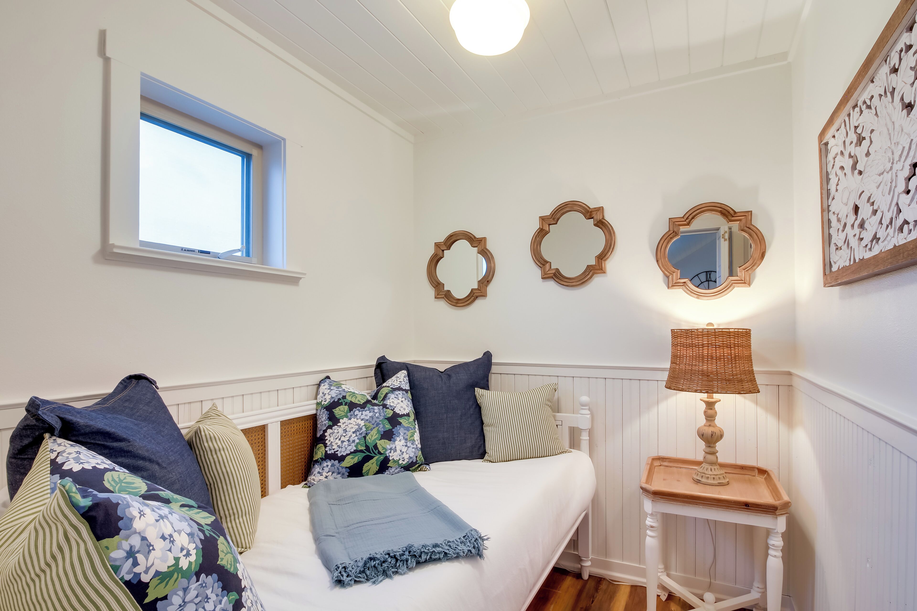A bedroom with a bed, a window, and a bedside table with a lamp.