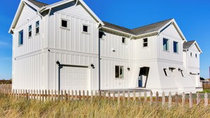 A white two-story house with a garage, a front porch, and a picket fence. - Scenic Bandon Vacation Rental w/ Beach Access! (Bandon)