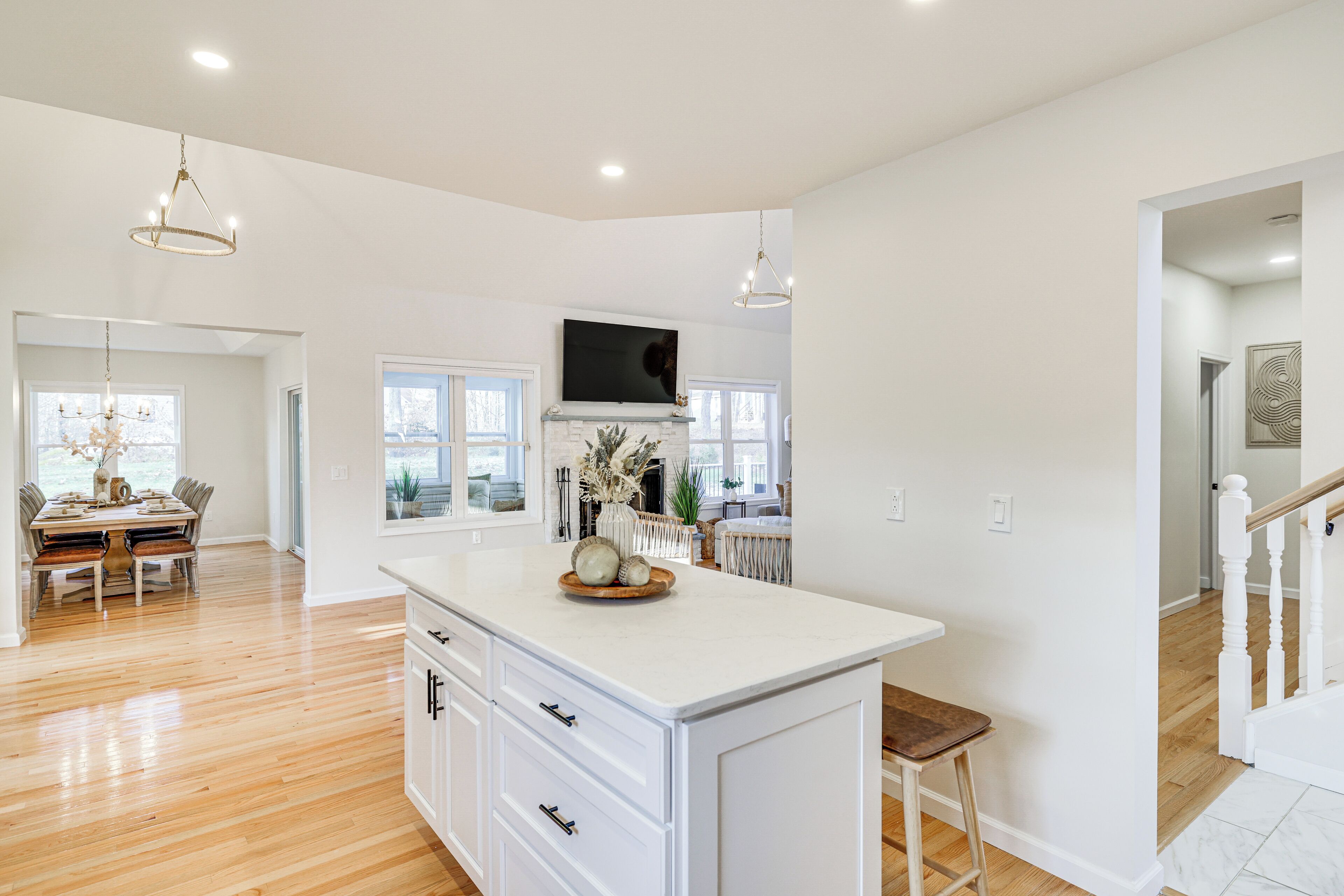 A spacious kitchen with a large island, wooden flooring, and pendant lighting.