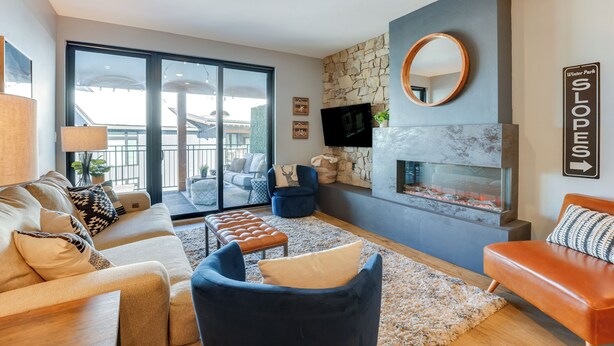 A modern living room with a stone fireplace, a large mirror, and a sofa set. - Downtown Winter Park Condo: Steps to Everything! (Winter Park)