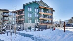 A multi-story residential building with balconies, a stone facade, and a snow-covered landscape. - Downtown Winter Park Condo: Steps to Everything! (Winter Park)