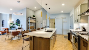 A modern kitchen with a central island, wooden flooring, and pendant lighting. - Downtown Winter Park Condo: Steps to Everything! (Winter Park)