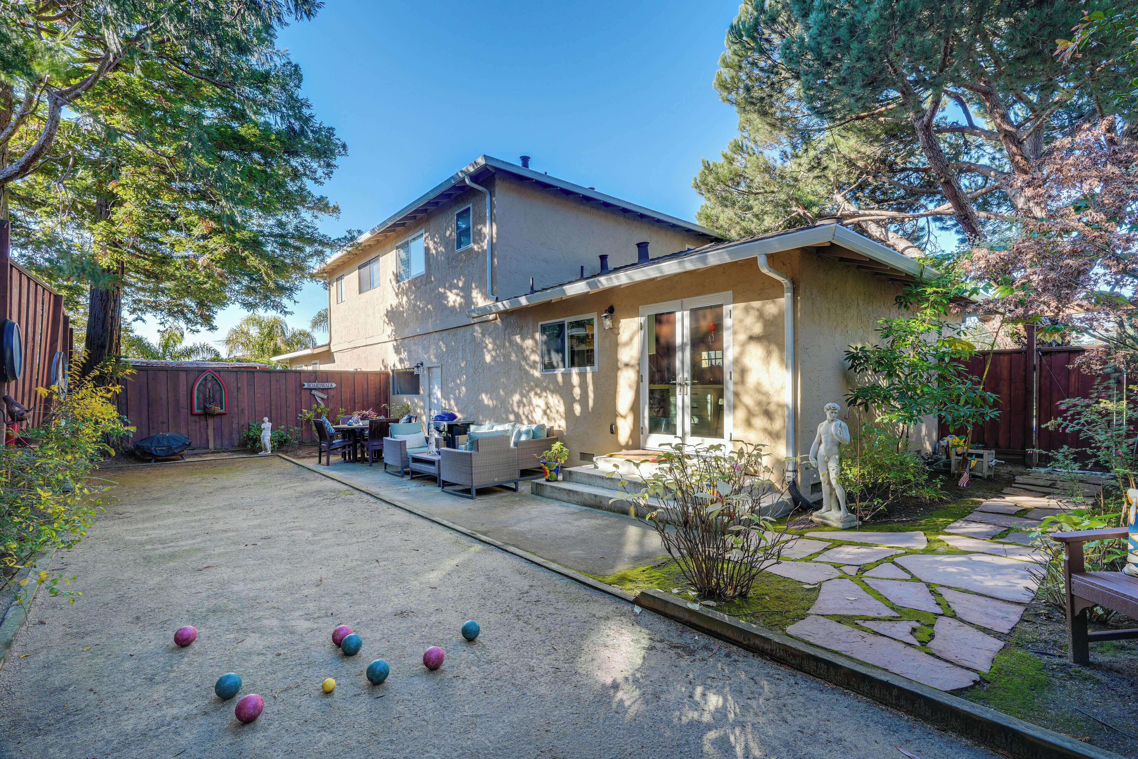 Ein Haus mit Garten, inklusive Terrasse, Sitzgelegenheit im Freien und einem Garten mit einer Statue.
