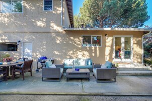 A patio area with outdoor furniture, a grill, and a door leading to a covered entrance.