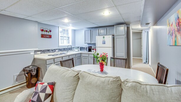Una cocina moderna con armarios blancos, una isla central y una zona de comedor con una mesa redonda y sillas.