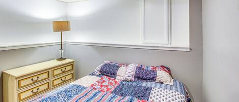 Een slaapkamer met een bed, een kaptafel, een lamp en een raam.