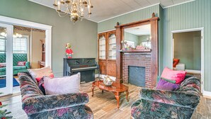 A living room with a grand piano, a fireplace, and a chandelier. - Historic Aberdeen Vacation Home w/ Yard! (Aberdeen)