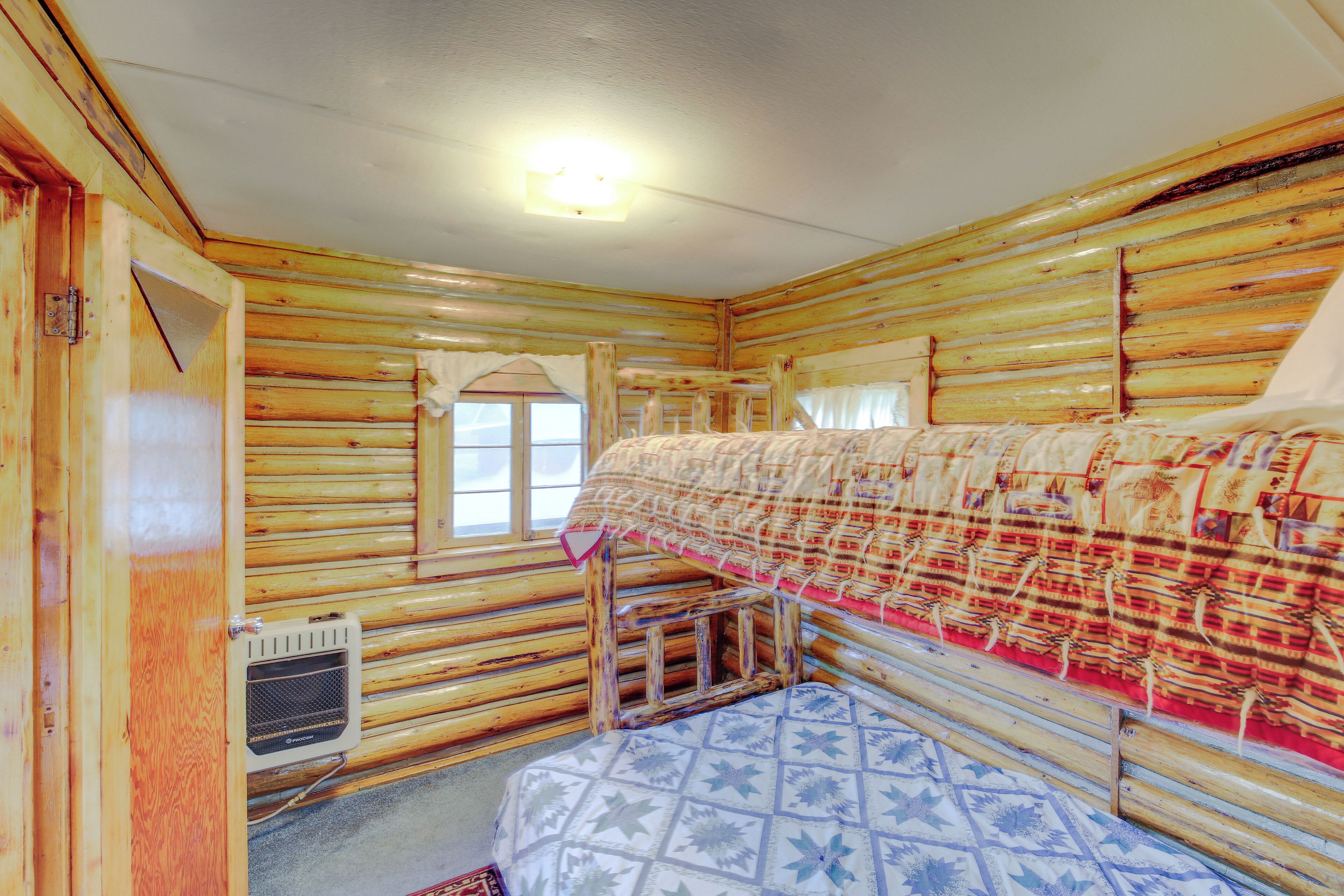 A log cabin room with a bunk bed, a window with curtains, and a ceiling light.