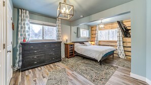Een slaapkamer met een bed, een dressoir en ramen.