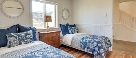 A bedroom with two beds, wooden flooring, and a window with a view.