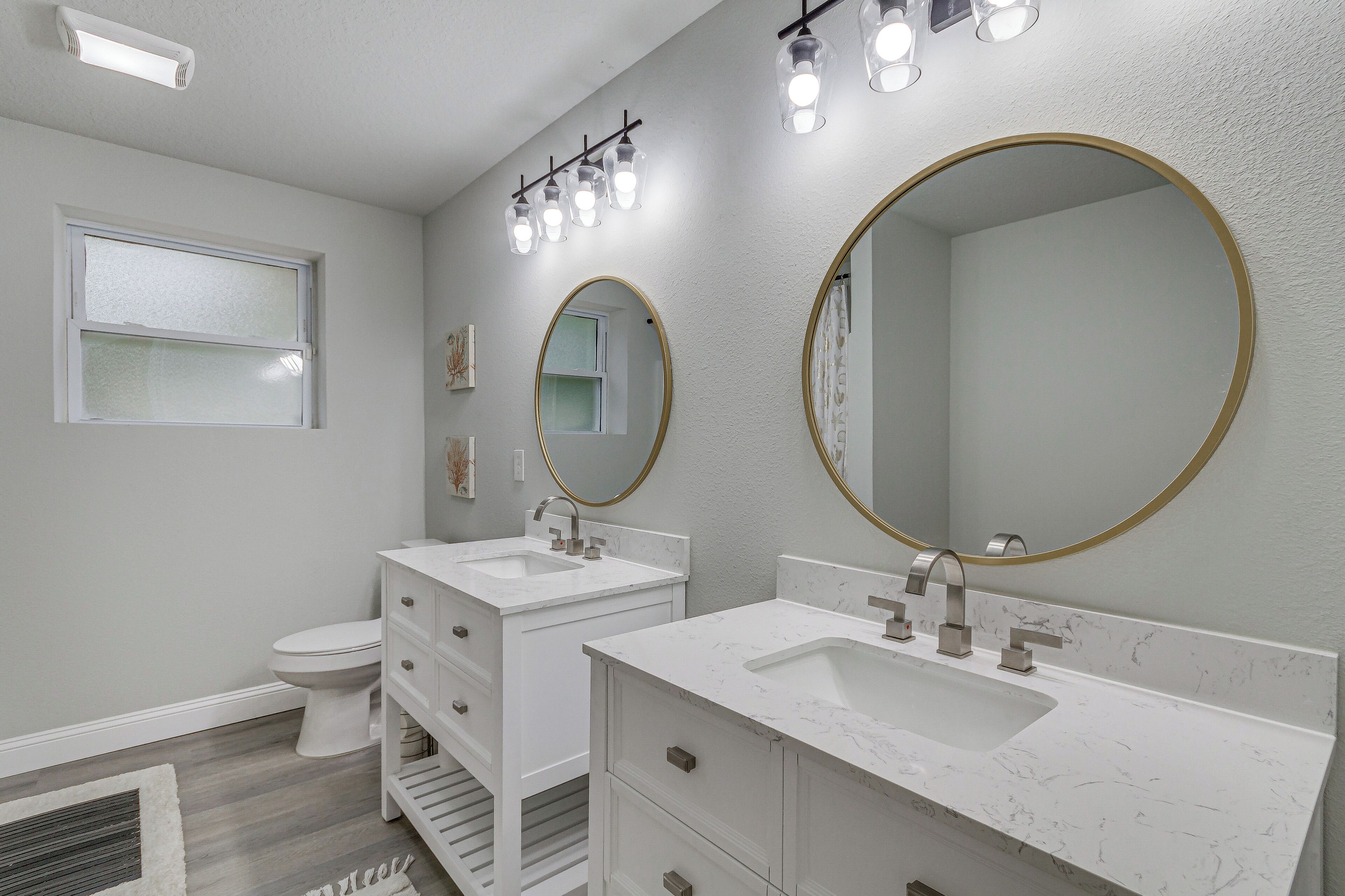 Een badkamer met twee wasbakken, een toilet en een raam.