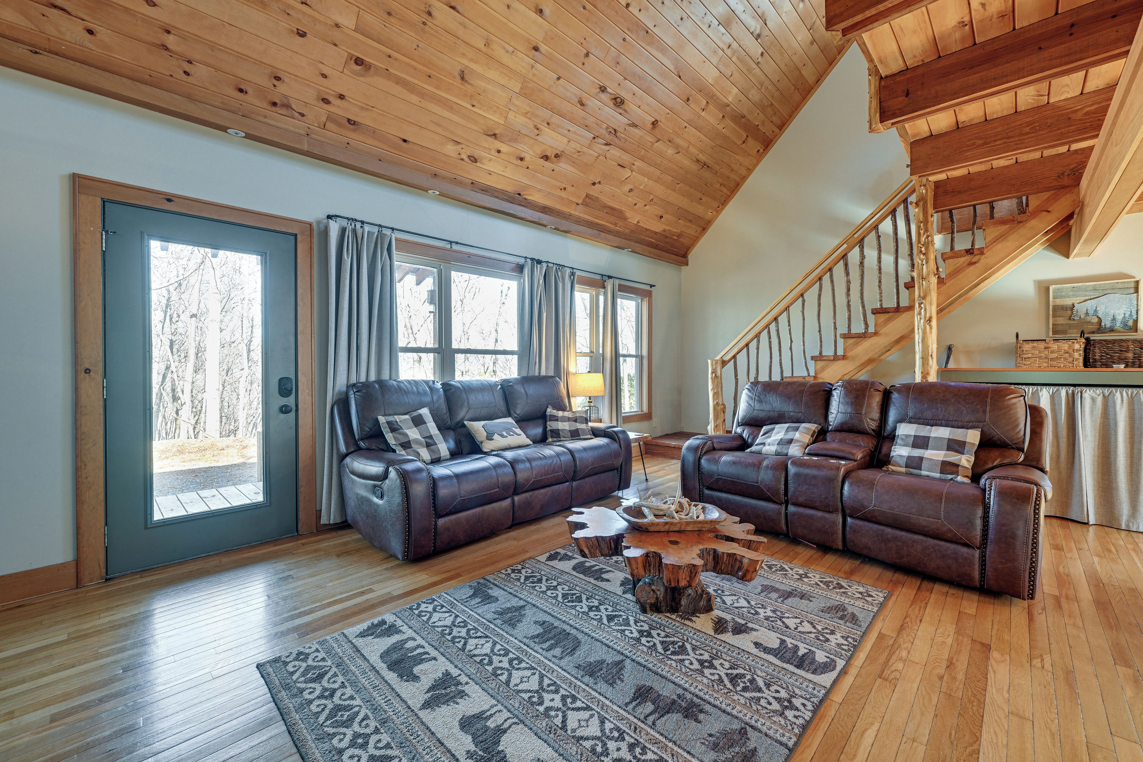 A spacious living room with two leather sofas, a wooden coffee table, and a patterned rug.