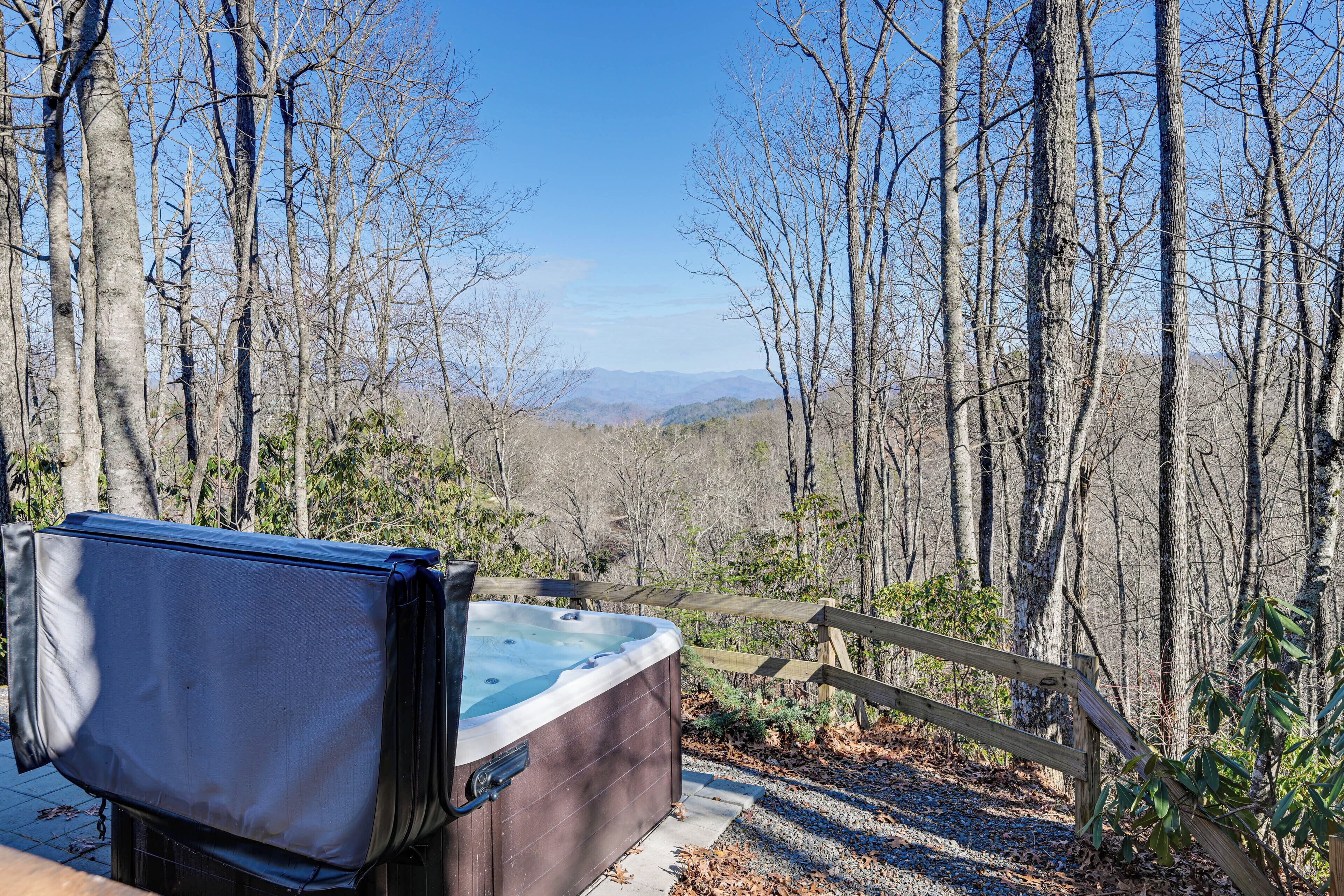 A hot tub in a forested area with a view of mountains.