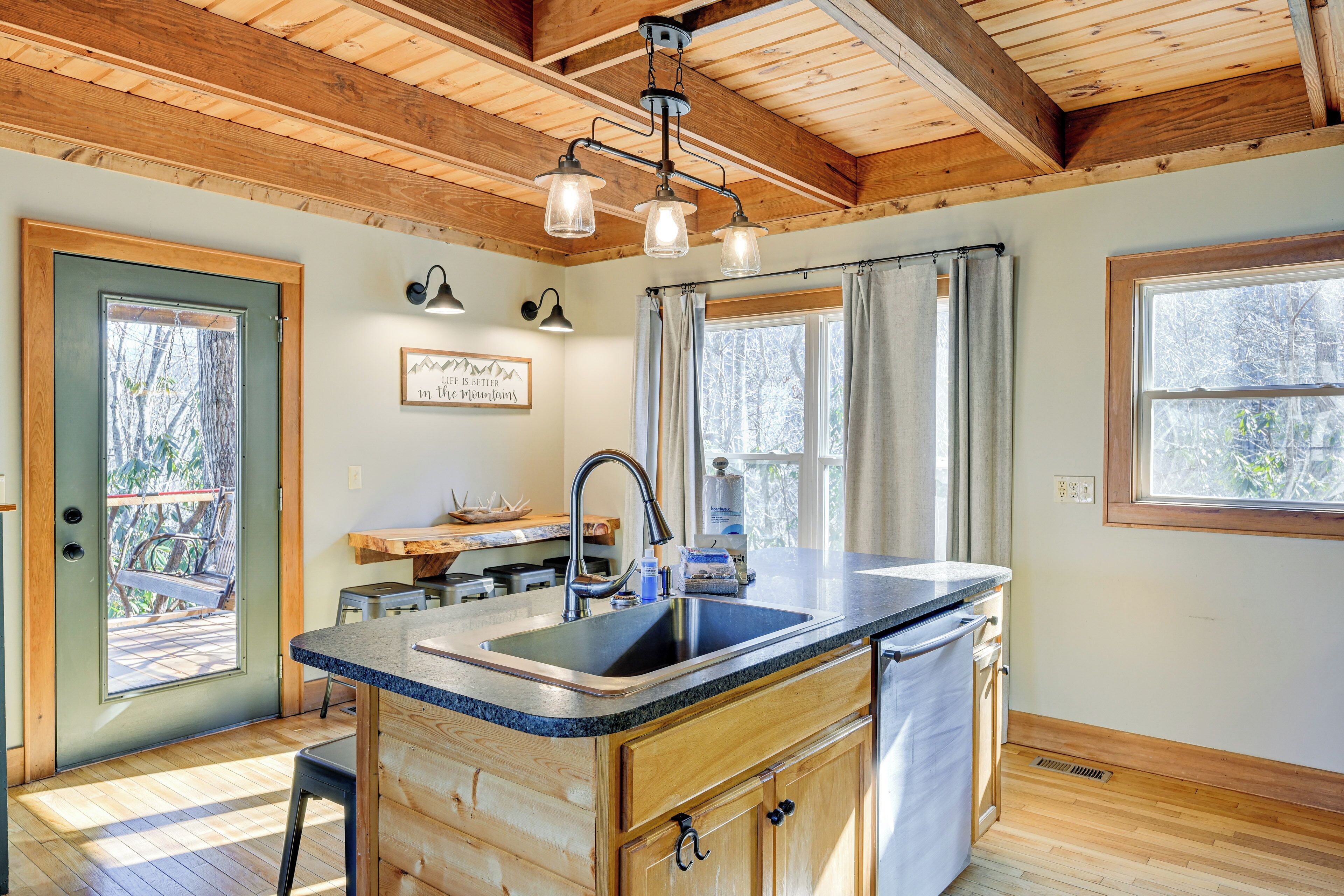 A kitchen with wooden cabinets, a granite countertop, a sink, and a hanging light fixture.