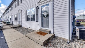 A row of white single-story houses with a front porch, a doormat, and a small step leading to the door.