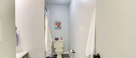 Une petite salle de bain comprenant des toilettes, une petite étagère avec des articles de toilette et un porte-serviettes.
