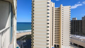 A high-rise building with multiple balconies overlooking a beach.