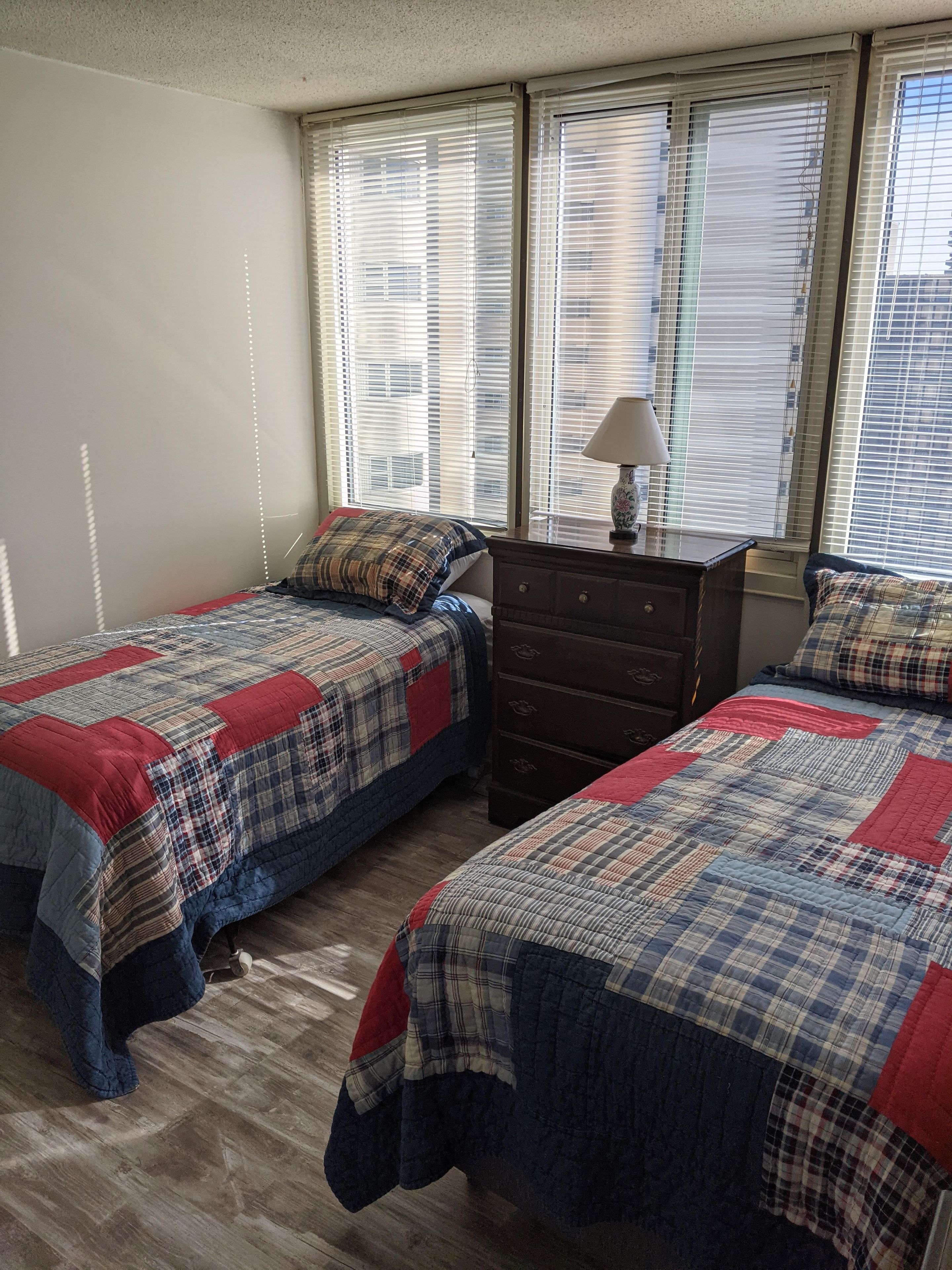 Un dormitorio con dos camas, un aparador y una ventana con persianas.