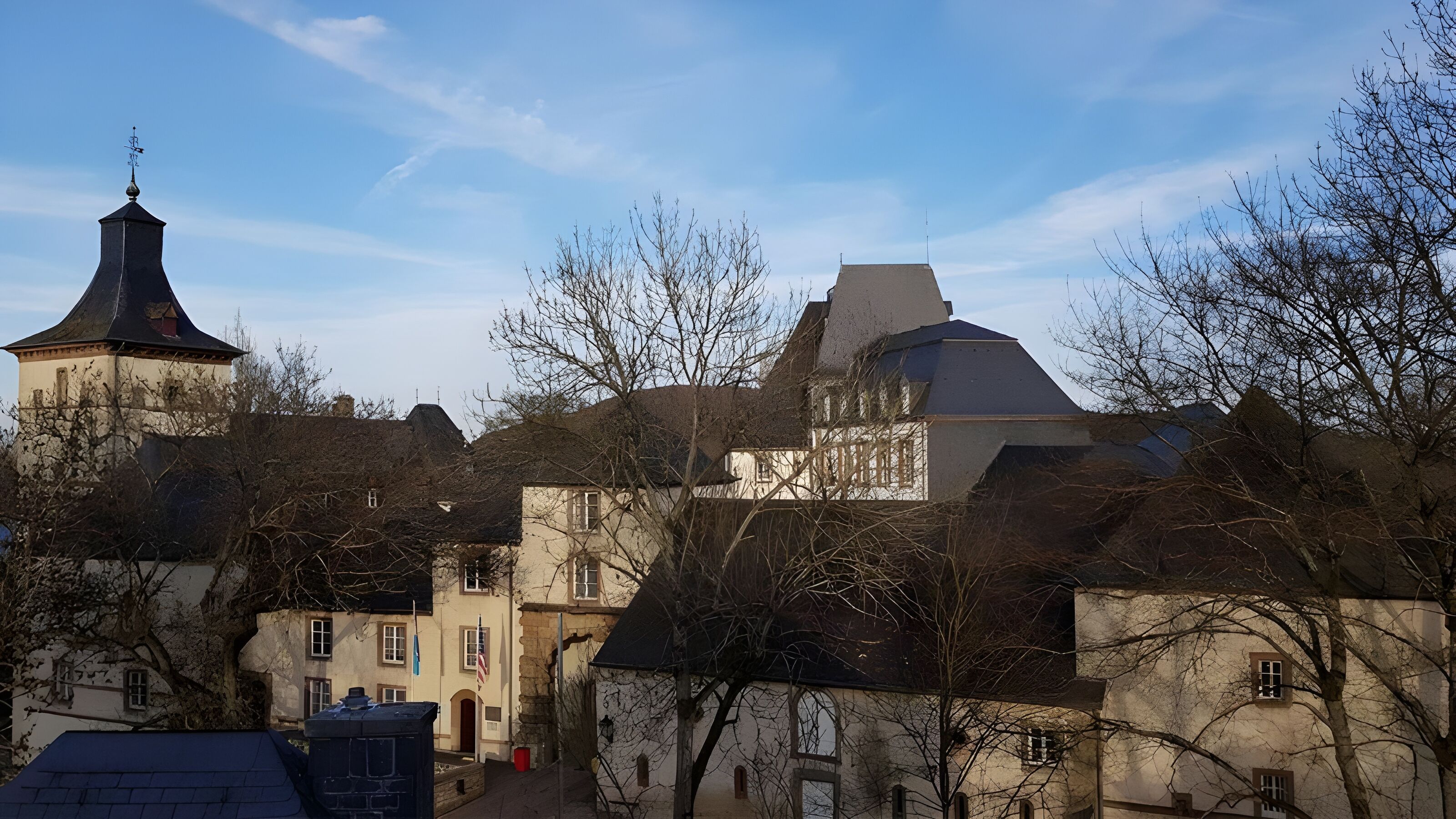 A historic building with multiple roofs and a prominent tower.