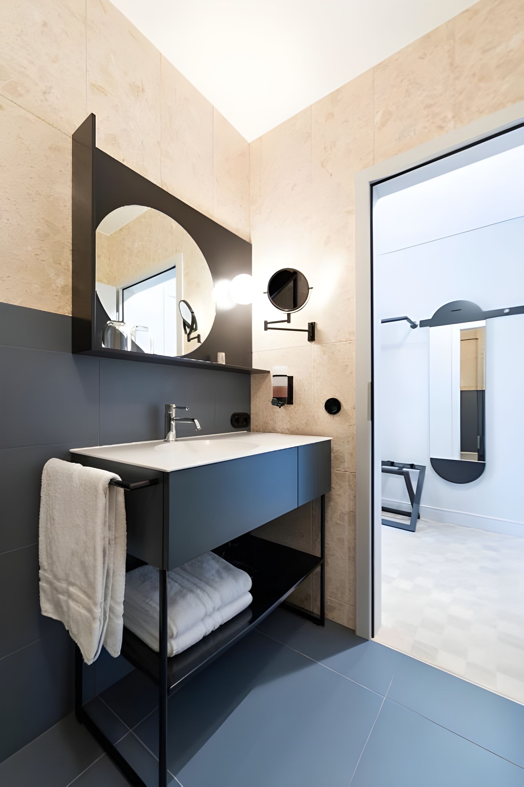 A modern bathroom with a black vanity, a large mirror, and a towel rack.