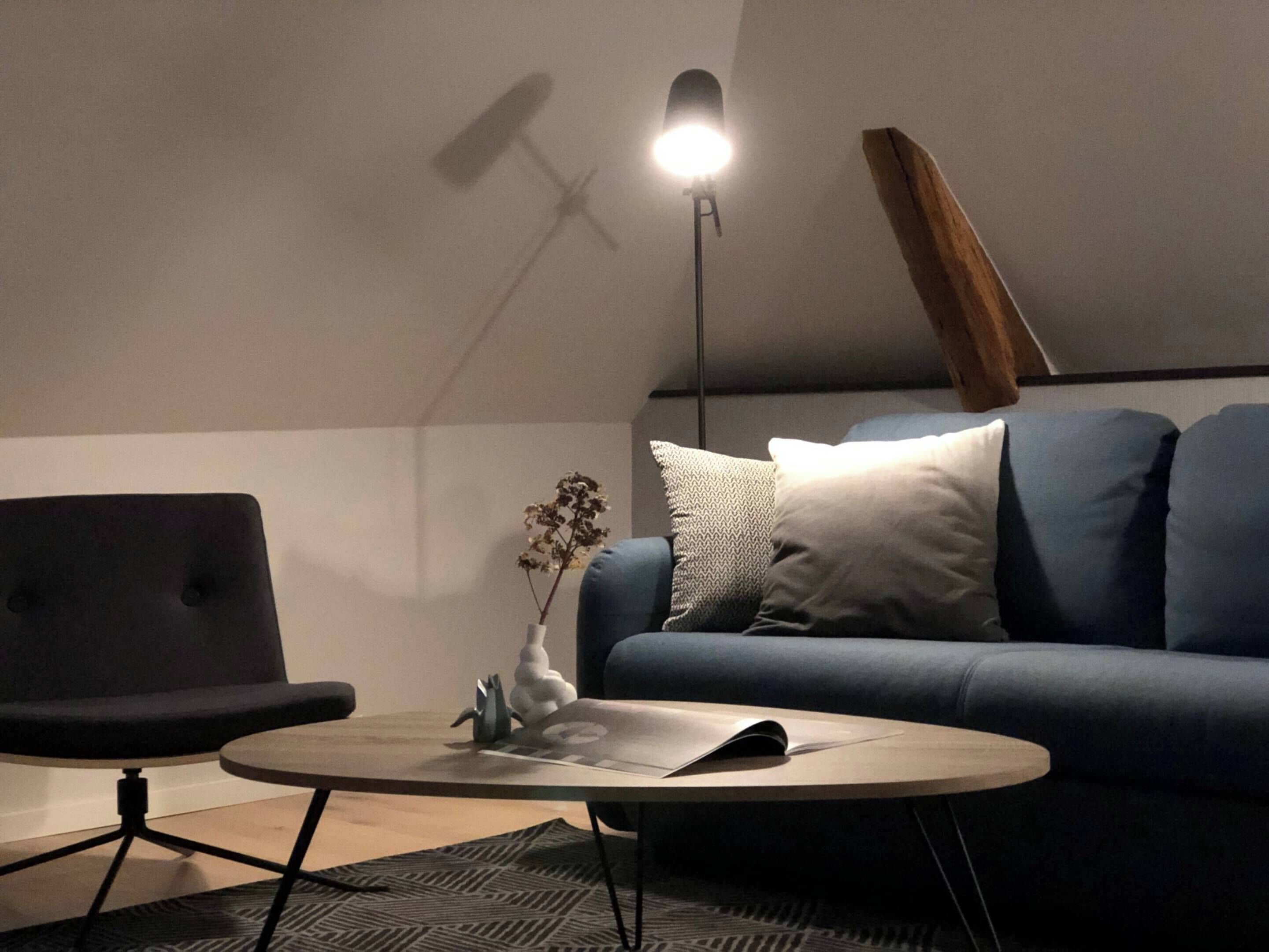 Una sala de estar moderna con un sofá azul, una mesa de centro redonda y una lámpara de pie.