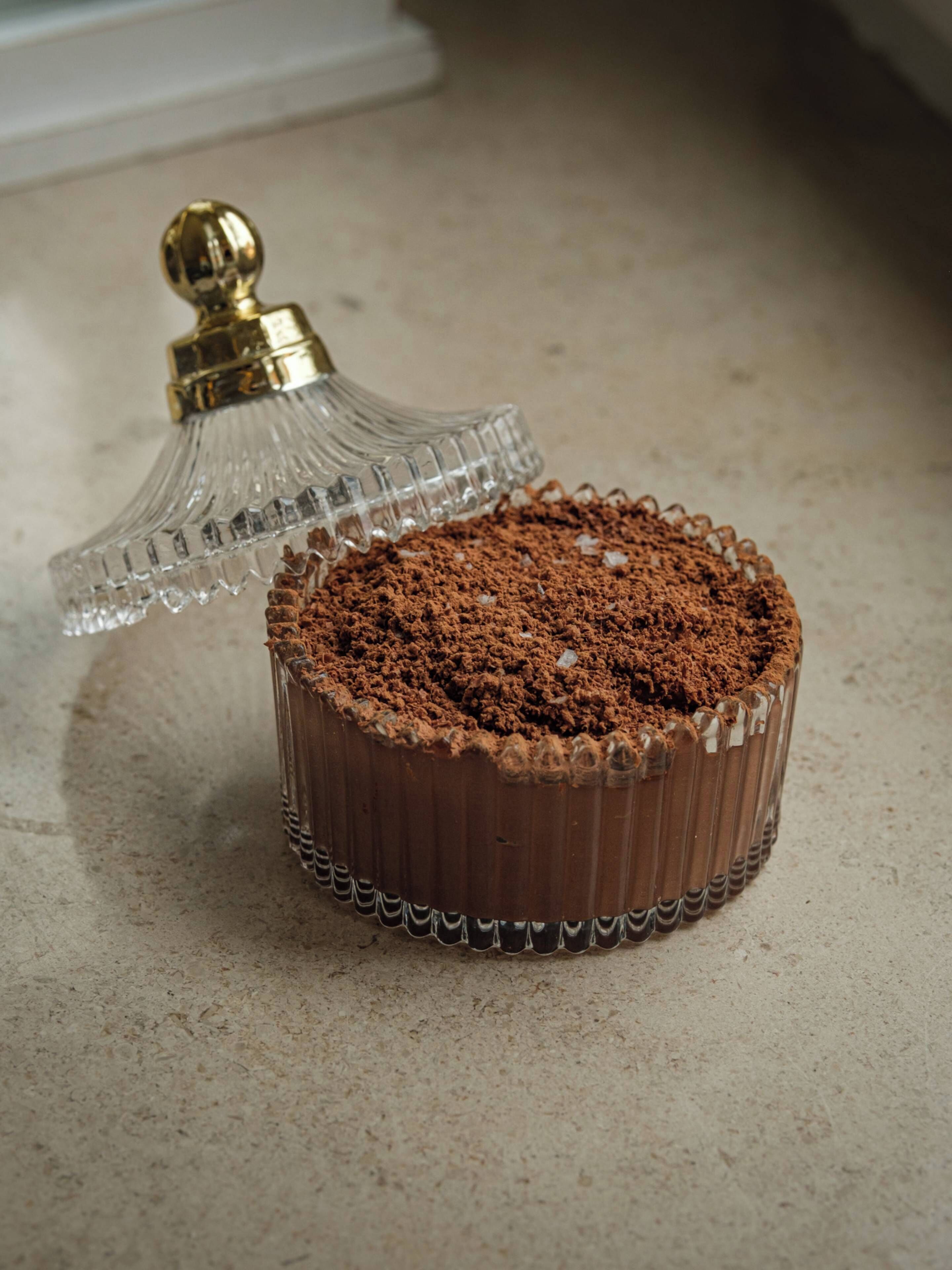 A round chocolate cake with a crumbly topping on a textured surface.