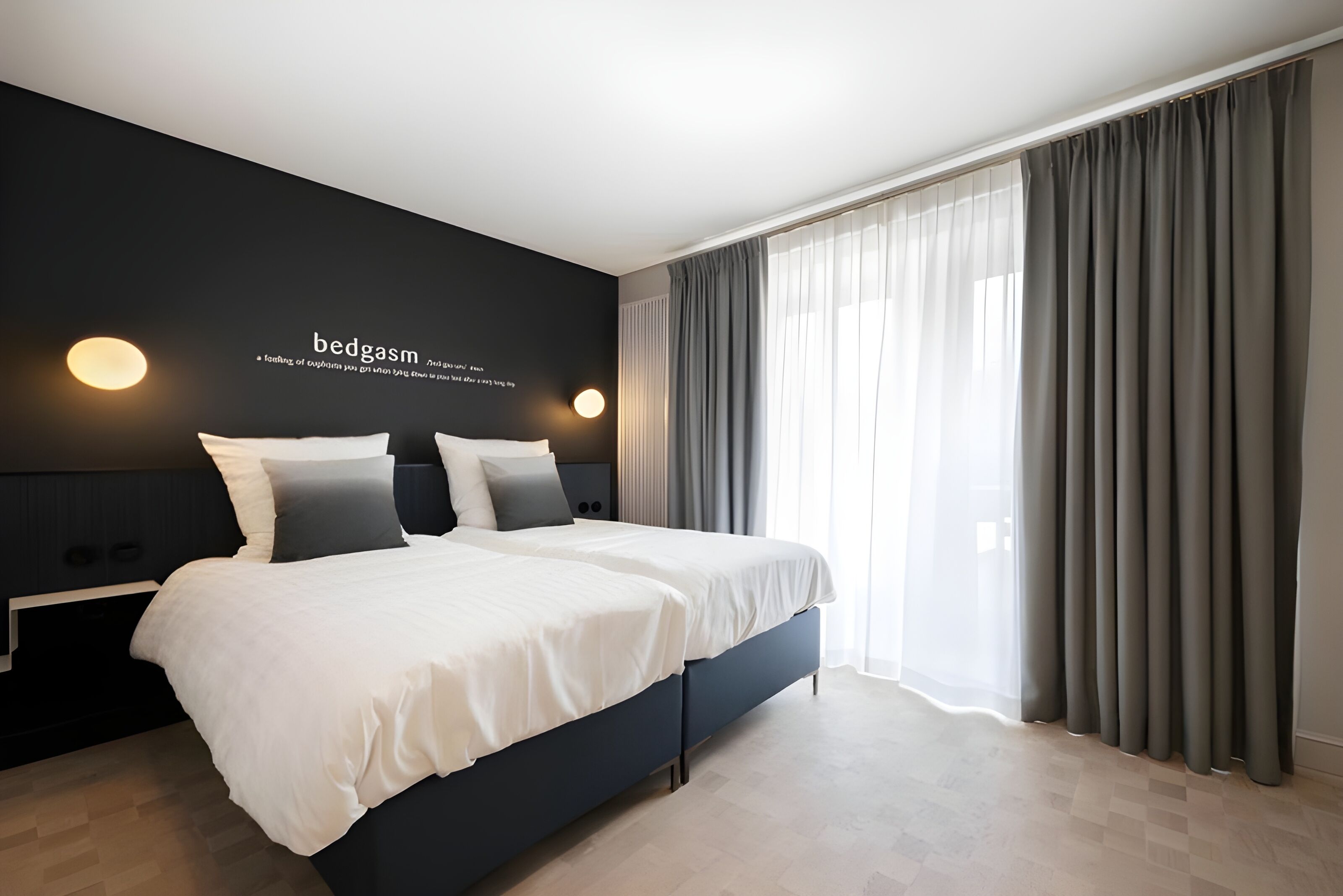 Een moderne slaapkamer met een groot bed, twee nachtkastjes en een wandlamp.