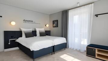 Un dormitorio moderno con cama, mesitas de noche, un banco e iluminación montada en la pared.