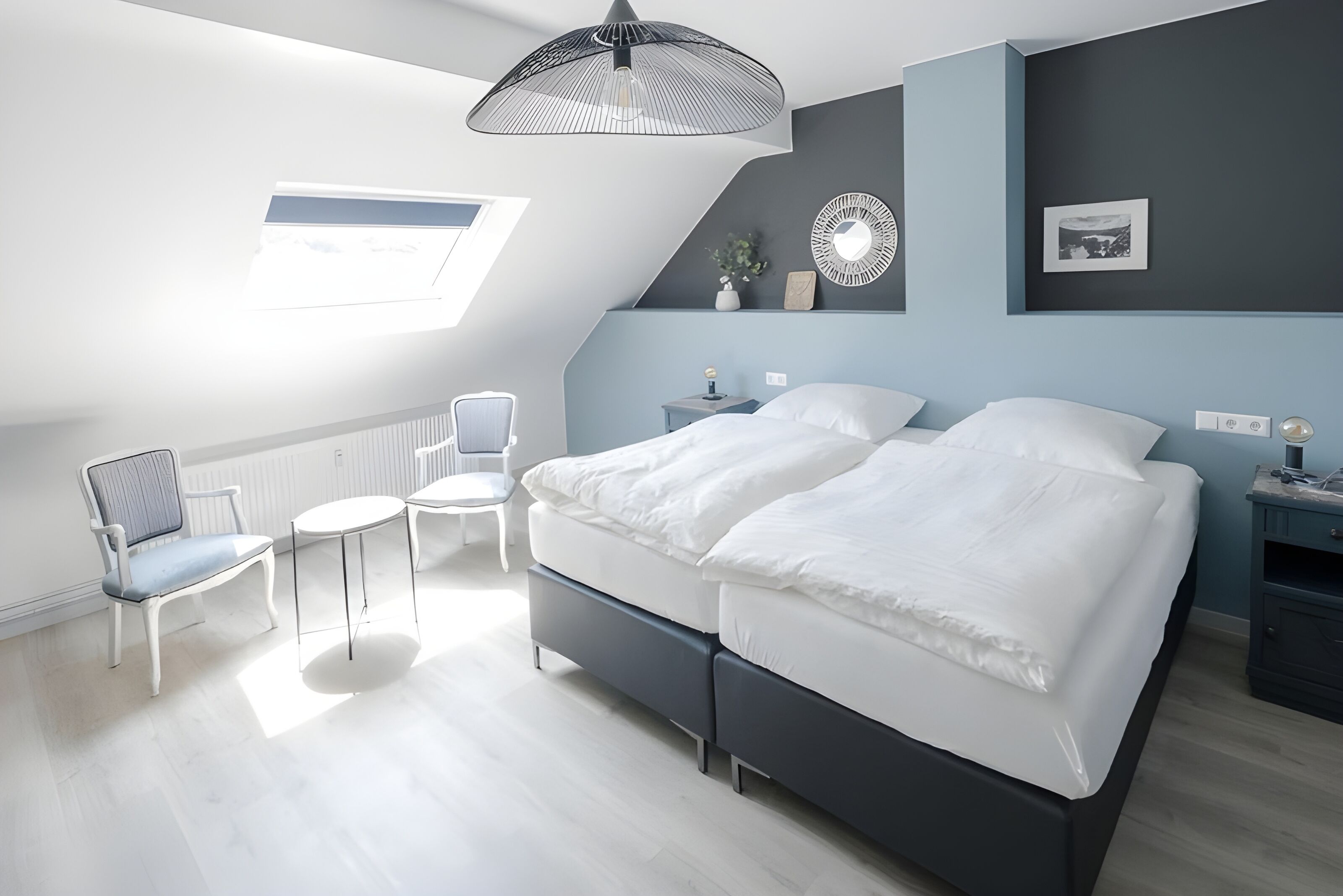 Ein modernes Schlafzimmer mit einem großen Bett, einem kleinen Tisch, einem Stuhl und einer Deckenleuchte.